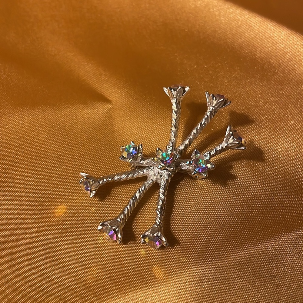Vintage silver pin with irredentist colored rhinestones. Rope design